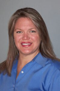 White woman with long hair wearing a blue shirt smiling